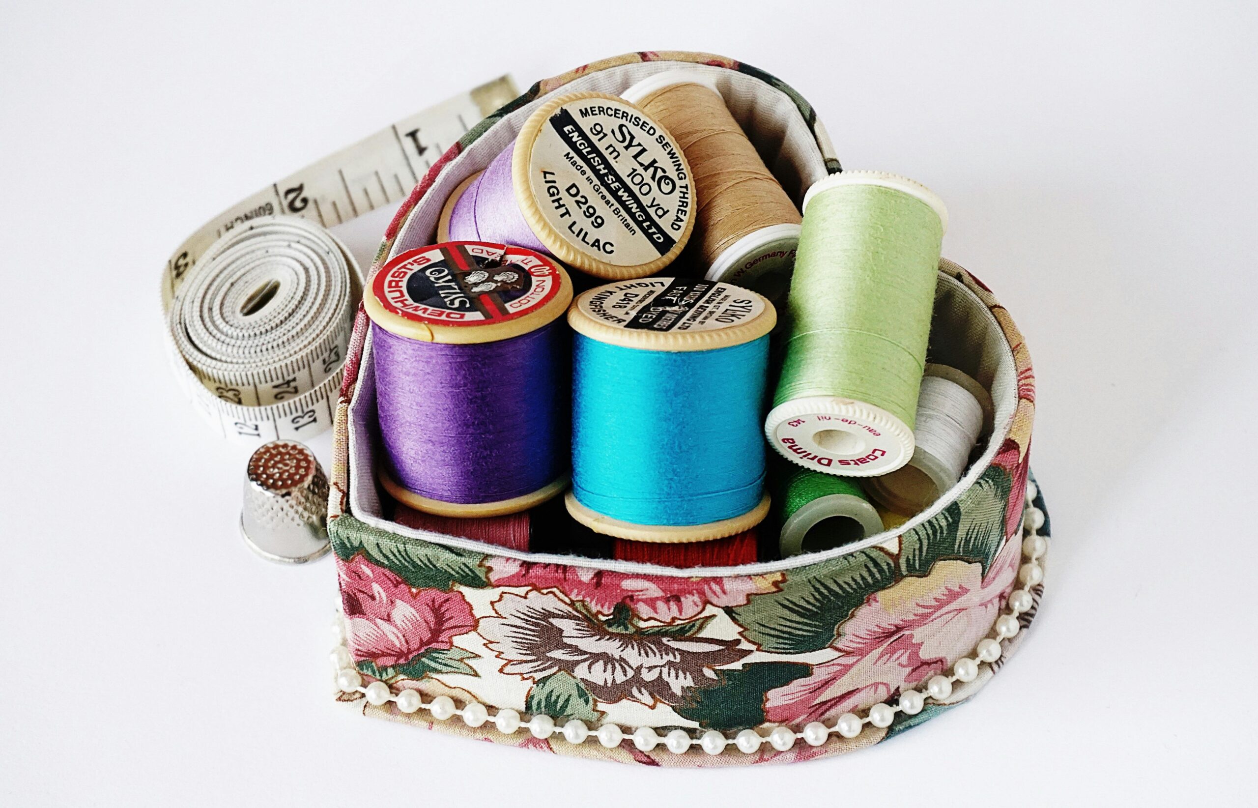 Collection of colorful sewing threads neatly arranged in a floral-patterned box, perfect for crafting inspiration.
