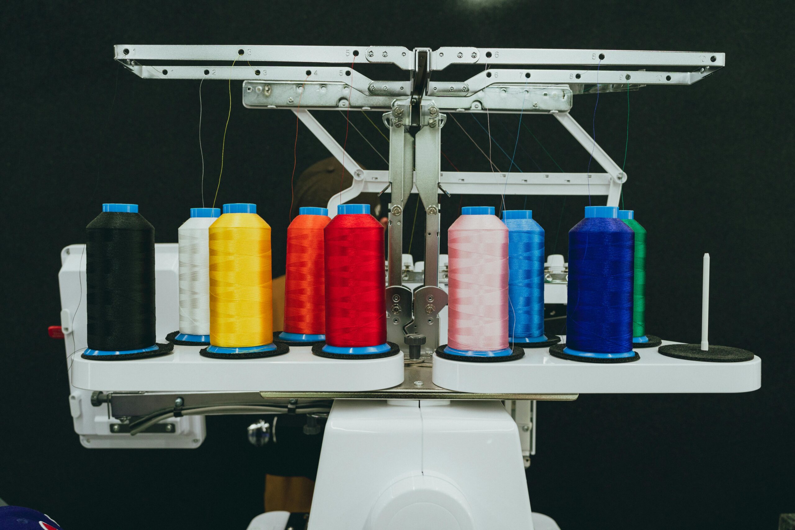 Close-up of colorful thread spools on an industrial embroidery machine in a textile workshop.